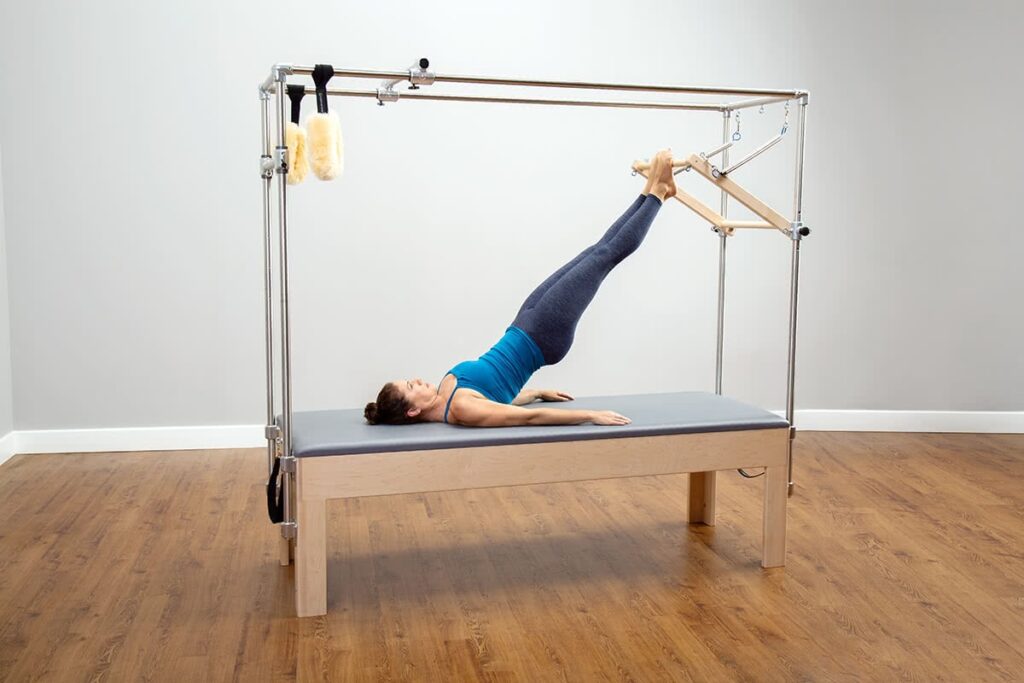 Pilates vingrinājums uz CenterLine Cadillac ar paceltām kājām.
