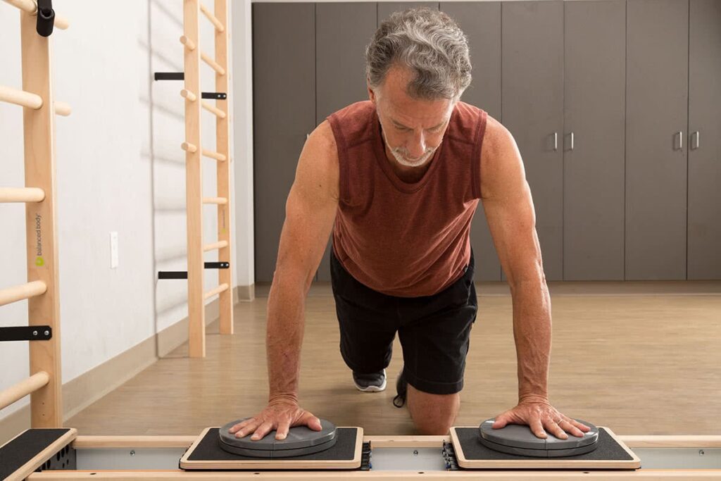 Мужчина выполняет упражнение планка на тренажёре CoreAlign в студии пилатеса