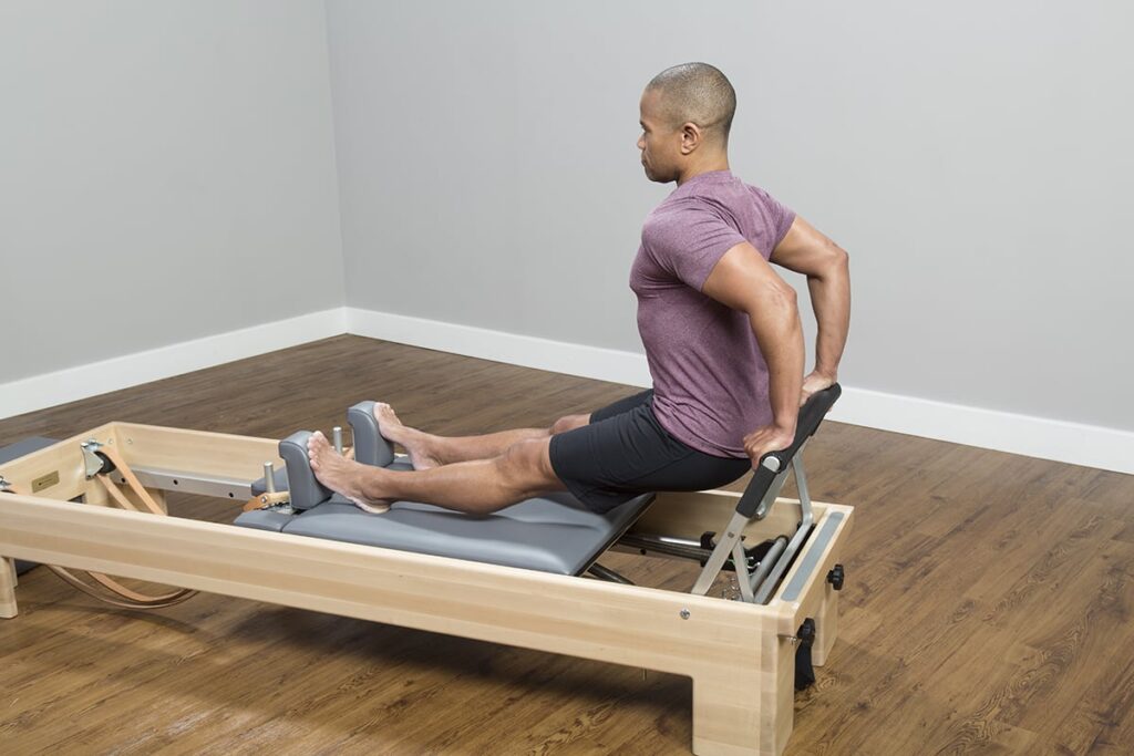 Persona vingro uz CenterLine Reformer, veicot Pilates vingrinājumus.