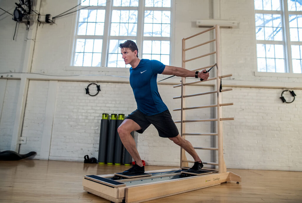 Мужчина занимается на тренажёре CoreAlign с настенной лестницей в студии.