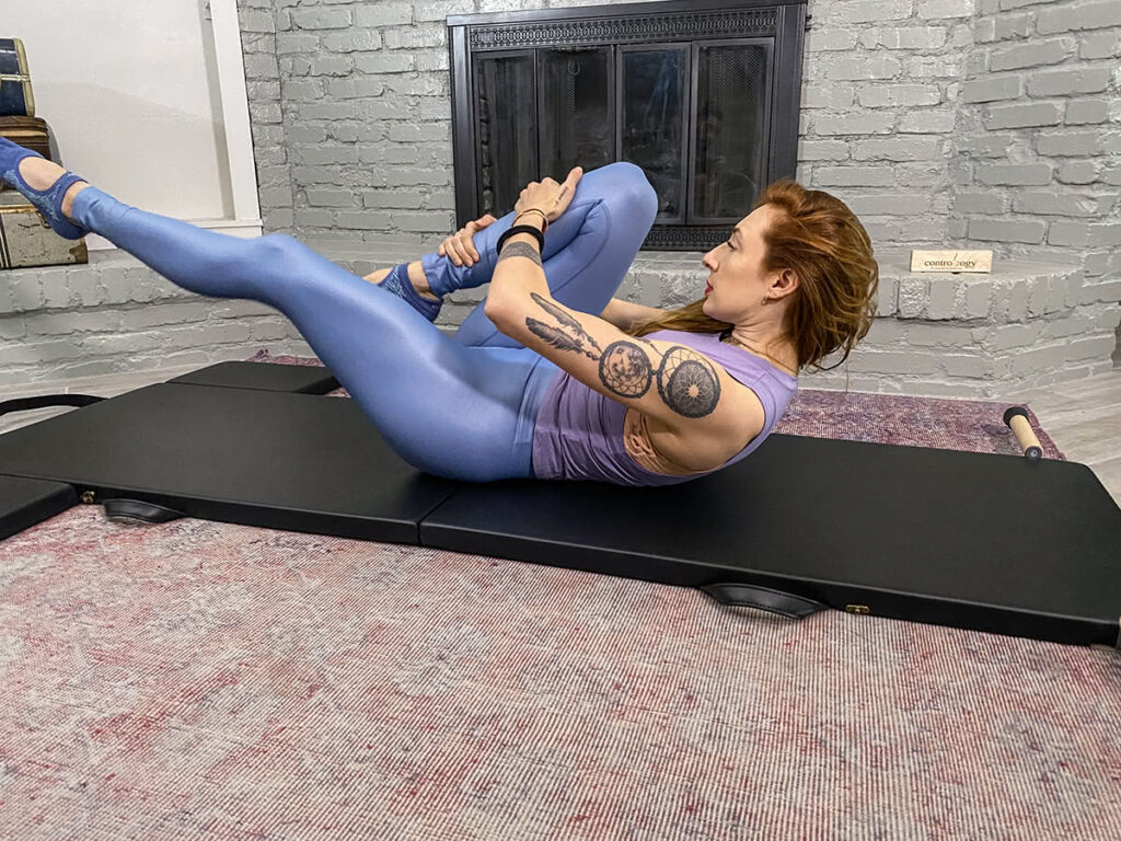 Persona vingro uz Contrology salokāmā vingrošanas paklāja Pilates studijā.
