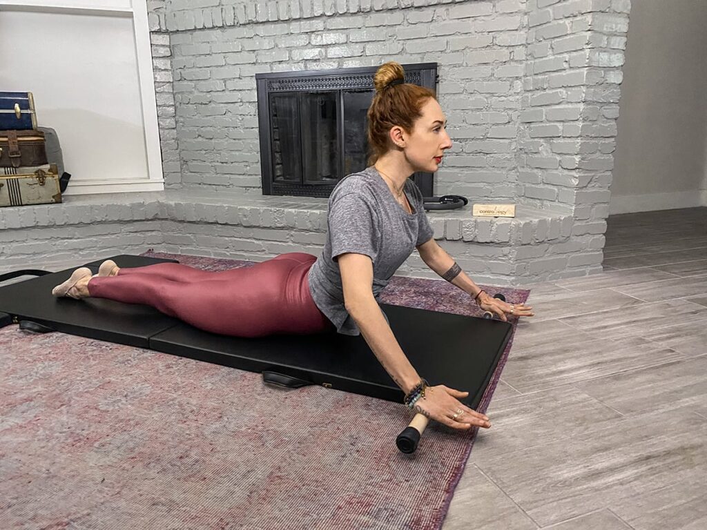 Sieviete praktizē Pilates uz Contrology saliekamā vingrošanas paklāja telpās.