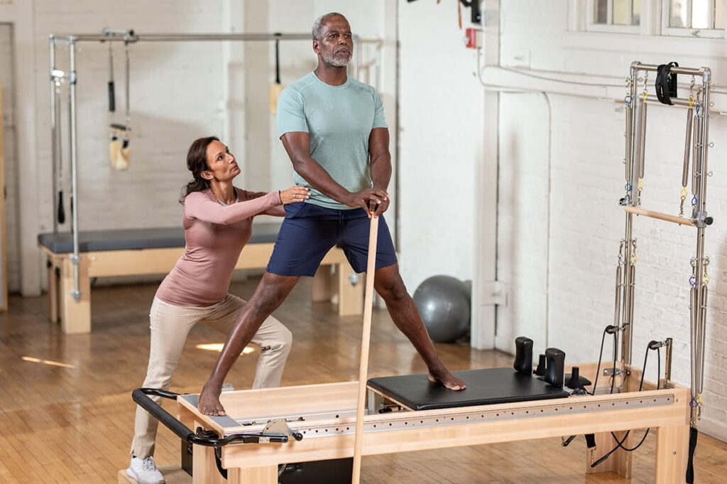 Instruktors palīdz klientam uz klīniskā reformera ar torni.