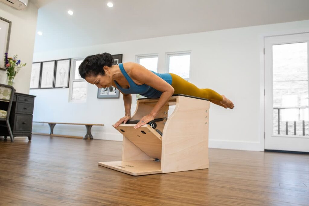 Instruktors demonstrē vingrinājumu uz Contrology Wunda krēsla.