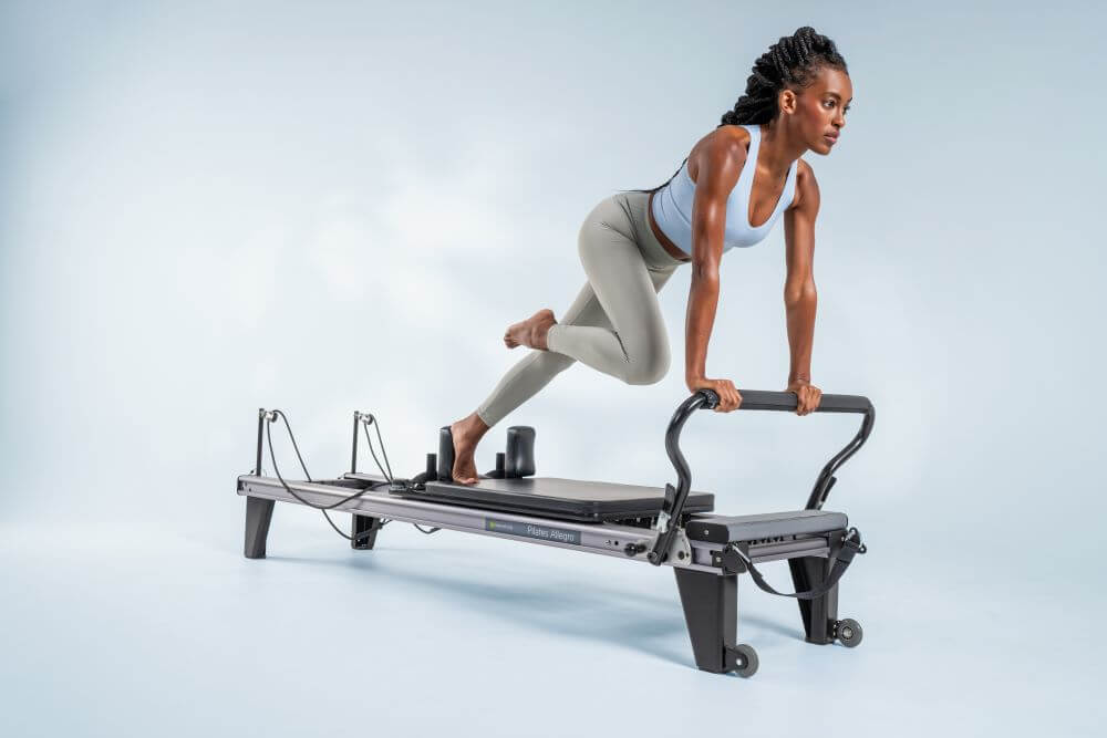 Sieviete vingro uz Allegro Reformer Pilates trenažiera.