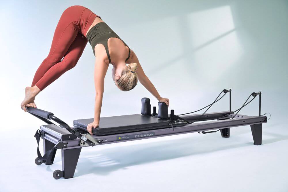 Persona vingro uz Allegro Reformer Pilates trenažiera