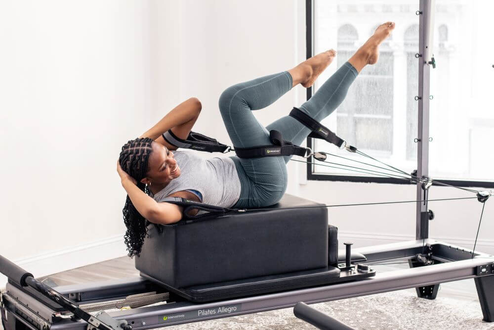 Человек занимается на тренажёре Allegro Reformer Konnector в студии.