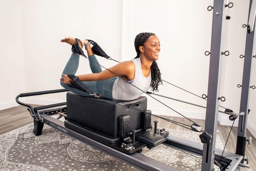 Человек использует Allegro Reformer Konnector для занятий пилатесом.