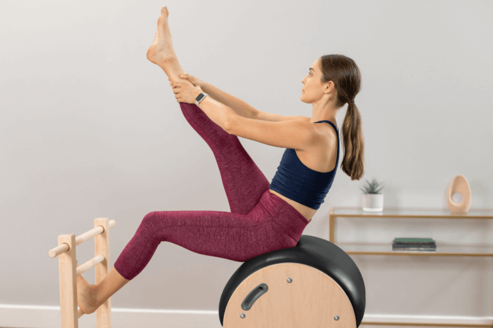 Pilates vingrinājums uz kāpņu mucas ar regulējamu slīdošo pamatni.