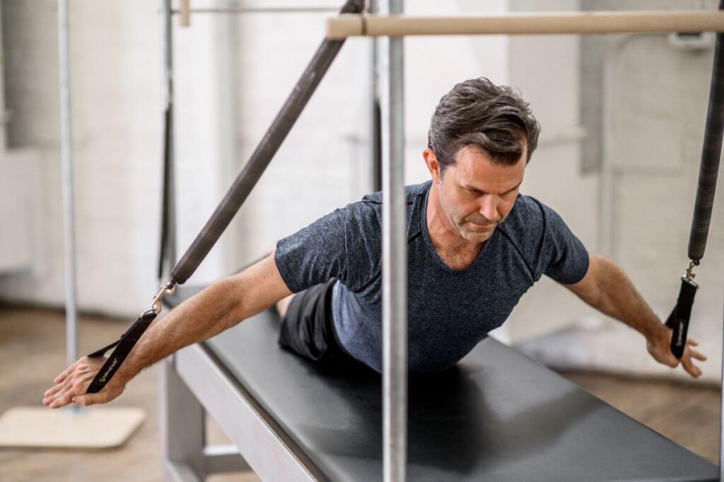 Vīrietis izmanto Contrology Cadillac JPack atsperes Pilates vingrinājumam