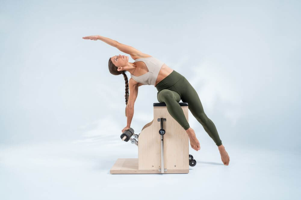 Pilates kombinētais krēsls, ko izmanto sānu izstiepšanas vingrinājumam.