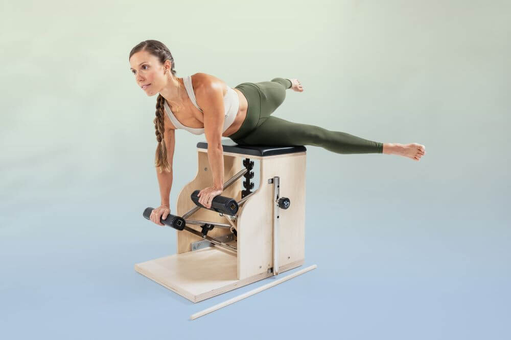 Sieviete vingro uz Balanced Body Combo Chair muskuļu stiprināšanai.