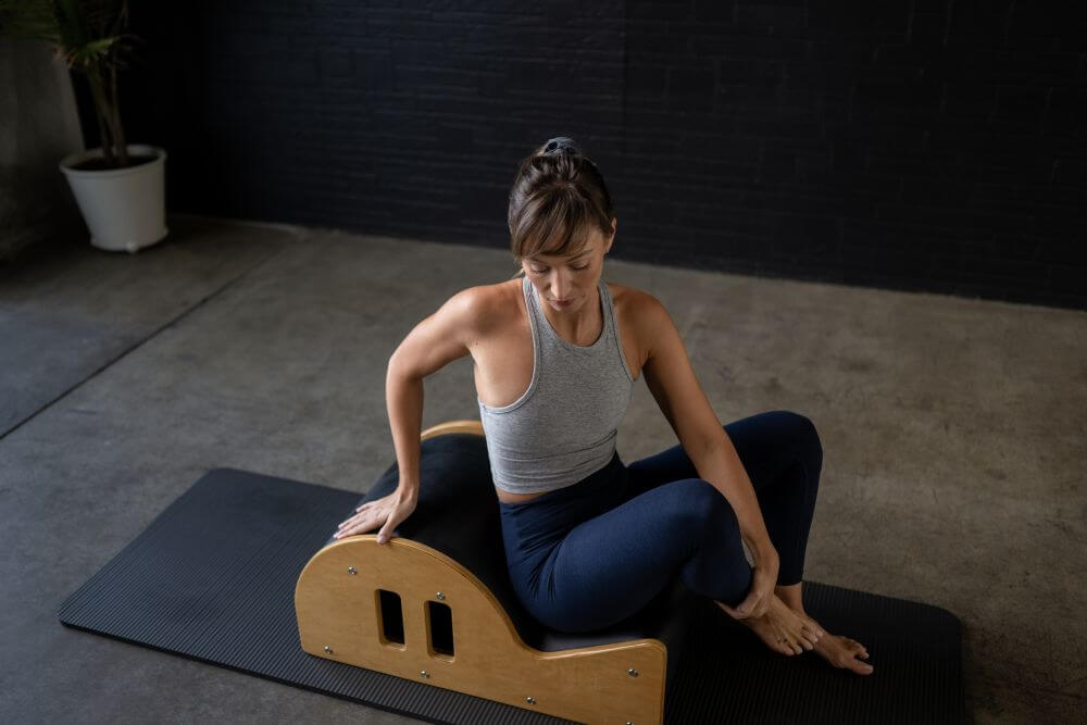 Pilates instruktore izmanto Clara Step Barrel uz vingrošanas paklāja.