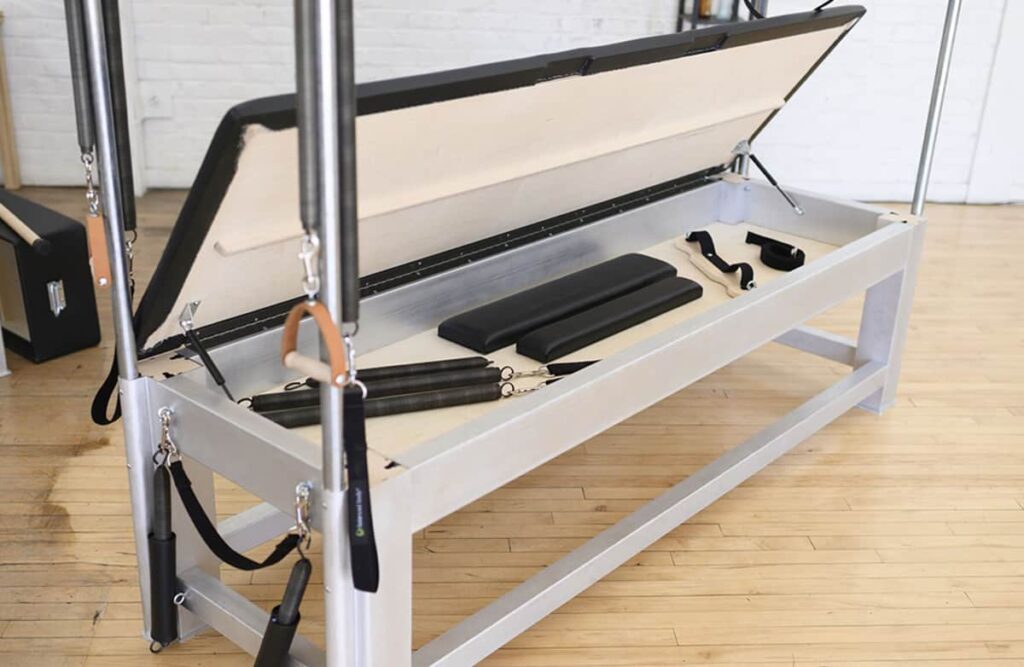 Contrology Cadillac atvērta rotaļlietu kaste ar Pilates piederumiem iekšā.