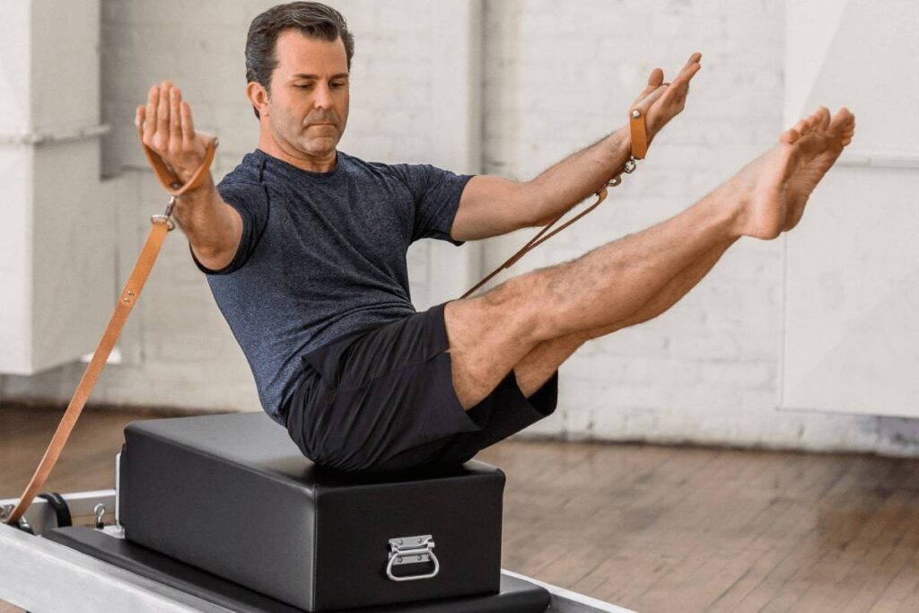 Vīrietis veic Pilates vingrinājumu uz Contrology kastes ar siksnām.