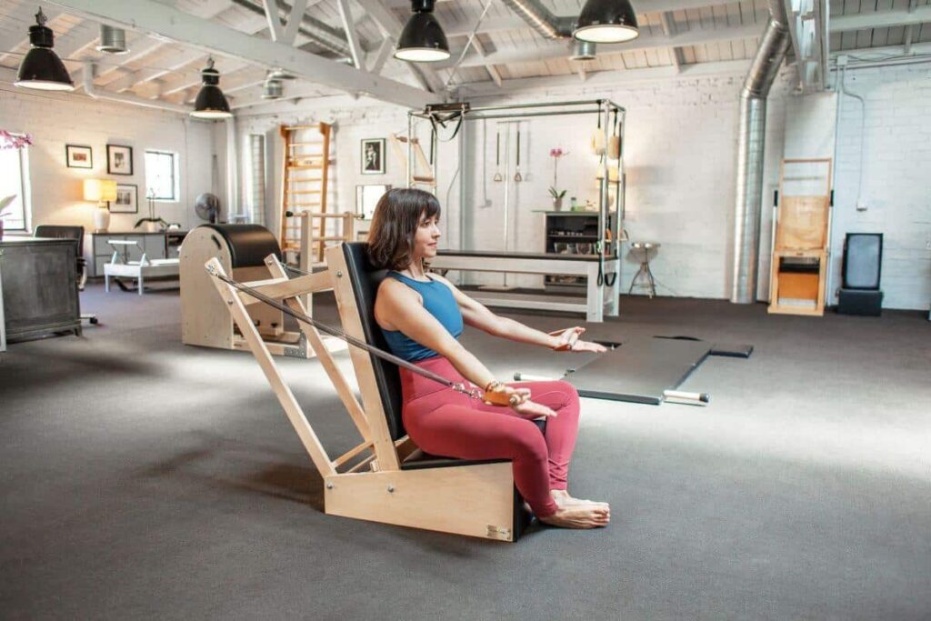 Pilates instructor using Contrology Contoured Leather Handles on Arm Chair.