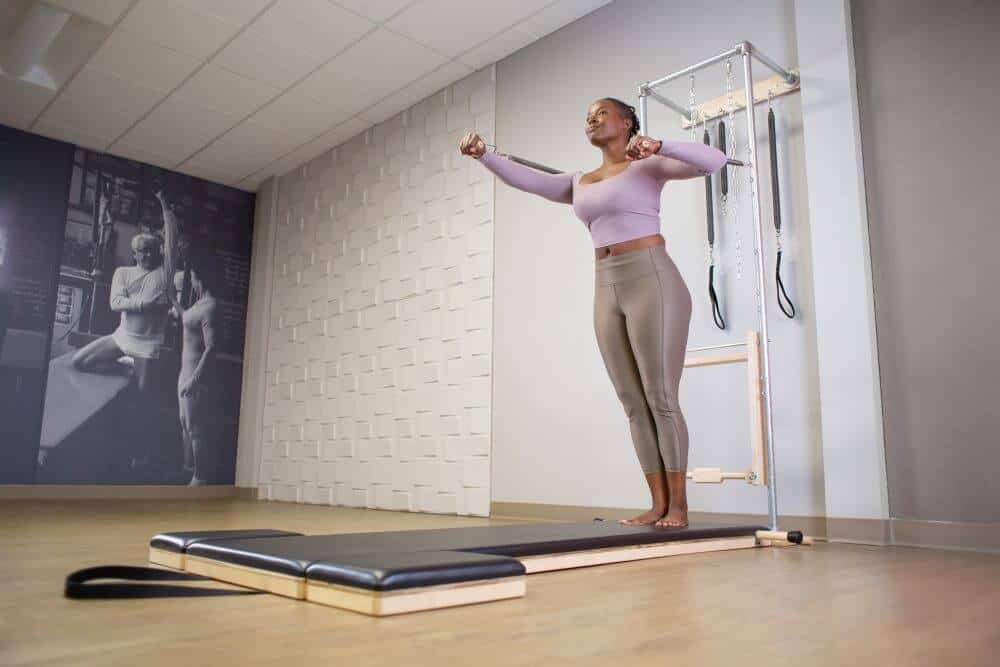 User performing exercise on a Contrology High Mat with Wall Tower.