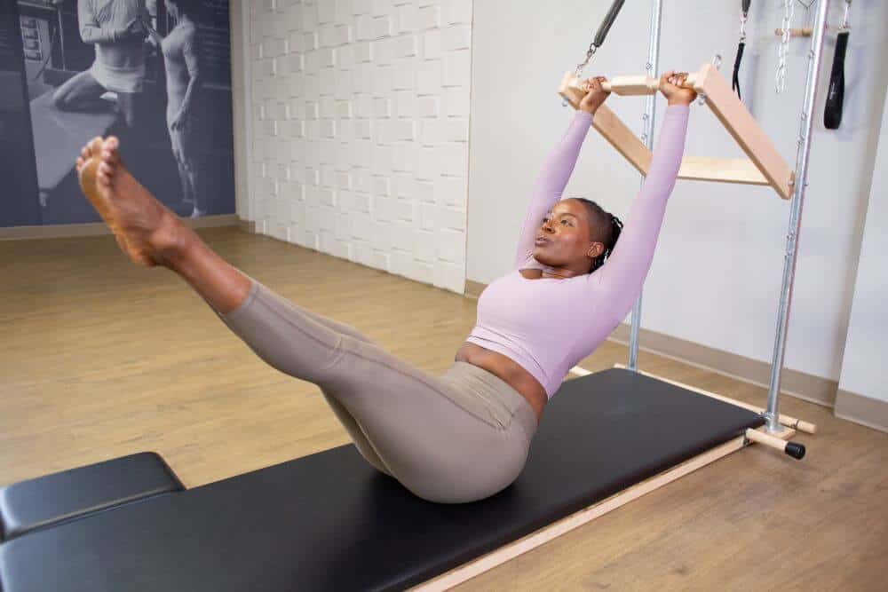 Woman exercising on Contrology High Mat with Wall Tower.