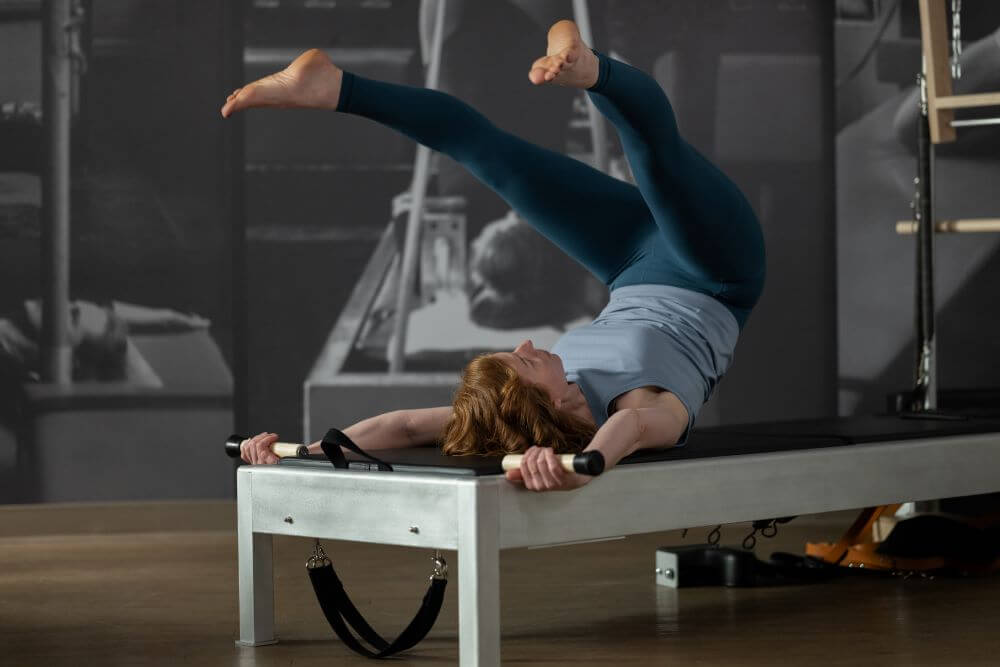 Sieviete vingro uz Contrology Reformer ar torni un vingrošanas paklājiņu