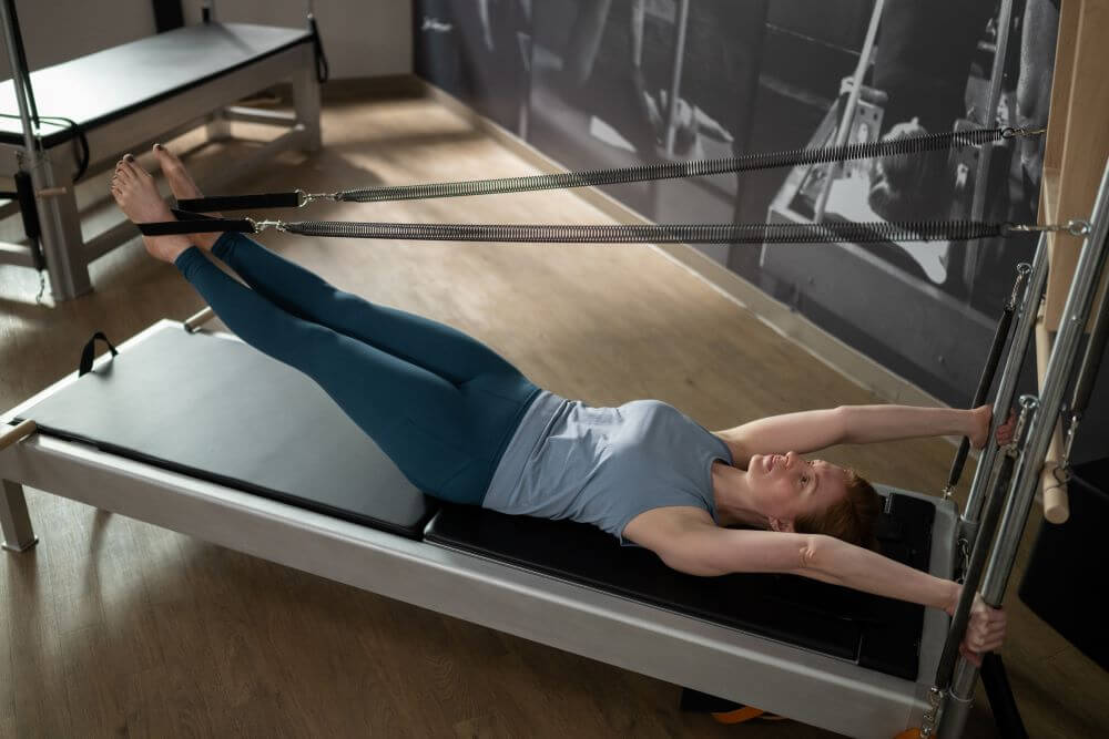 Persona vingro uz Contrology Reformer ar torni un paklājiņu.