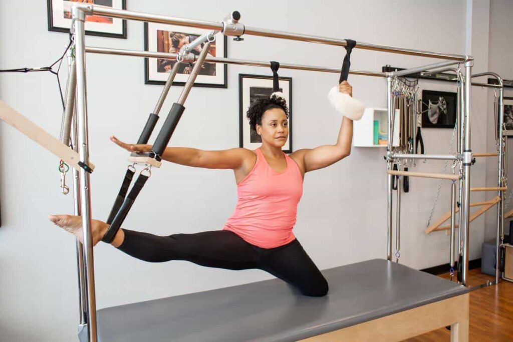 Woman using Balanced Body Cotton Web Straps on trapeze table.