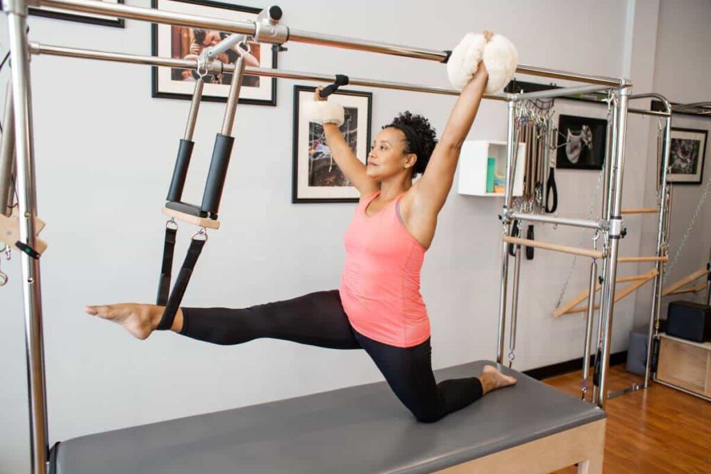 Person using Cotton Web Straps with Fuzzies on Pilates Cadillac.