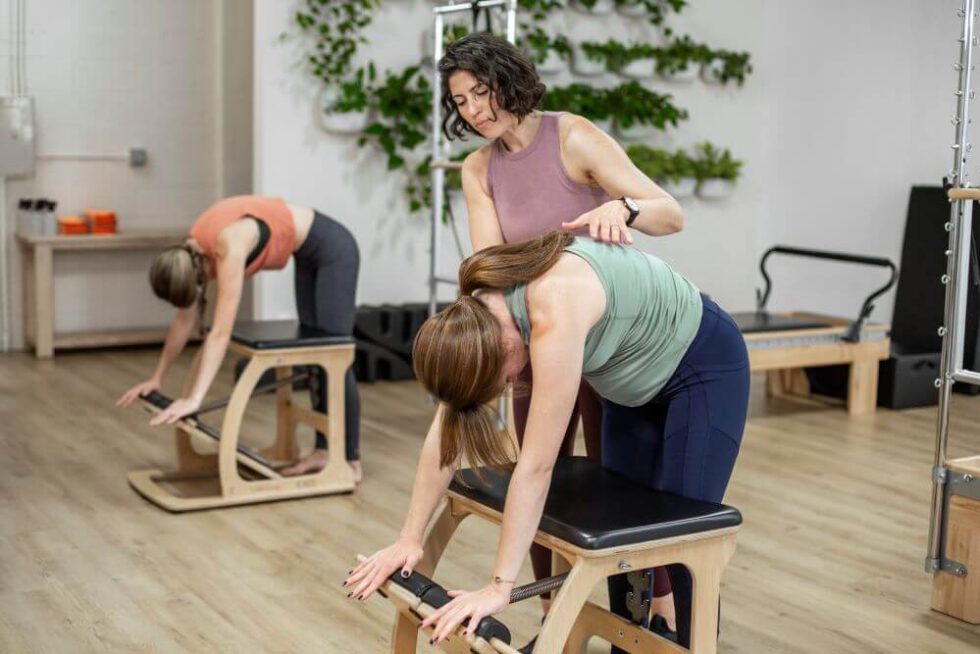 Instruktors palīdz studentam uz EXO Chair Pilates nodarbības laikā.