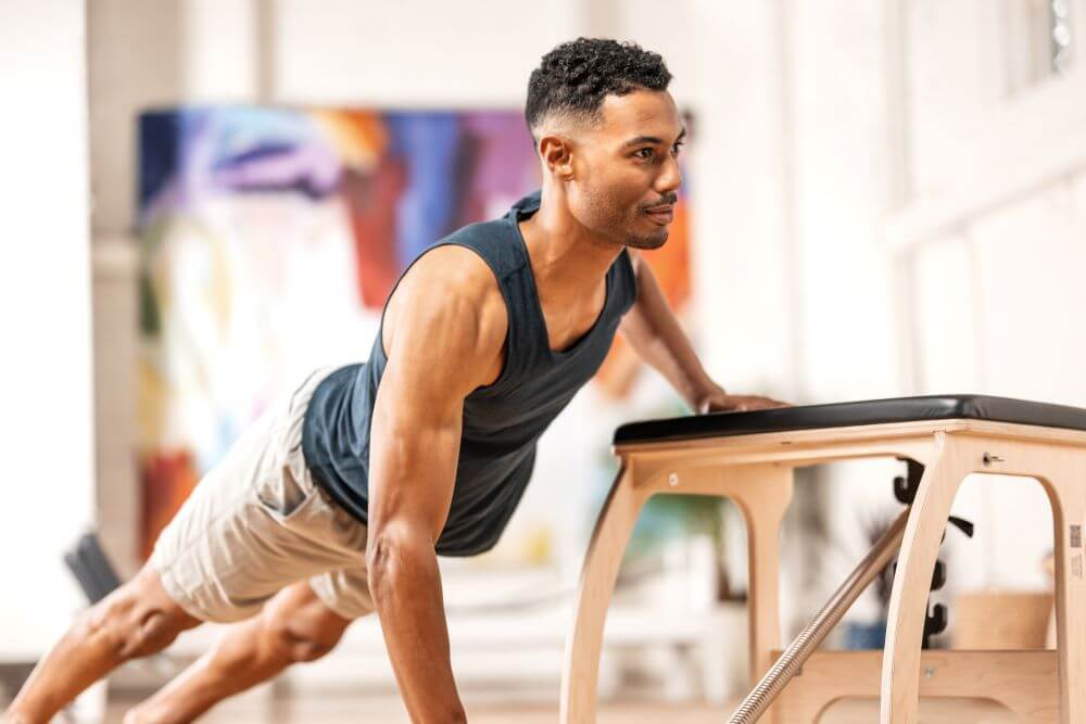 Cilvēks vingro uz Pilates EXO Chair pilnvērtīgam visa ķermeņa treniņam