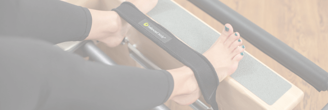 Ступни в ремнях Balanced Body на реформере для пилатеса.