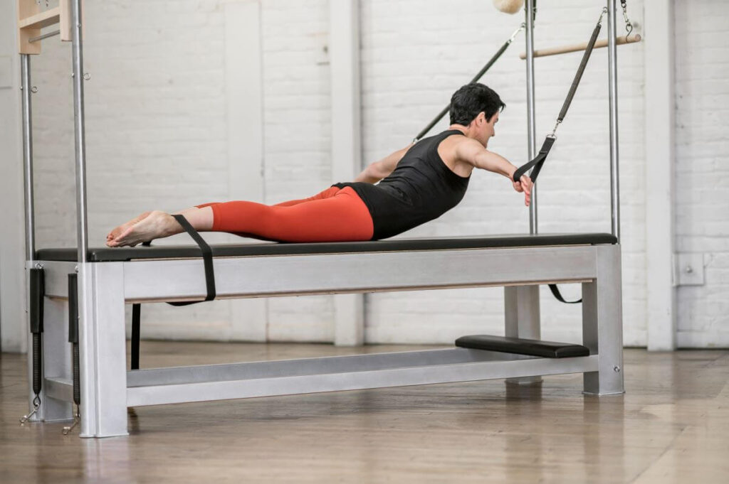 Instruktors izmanto Contrology Cadillac ar JPack atsperēm Pilates nodarbībā
