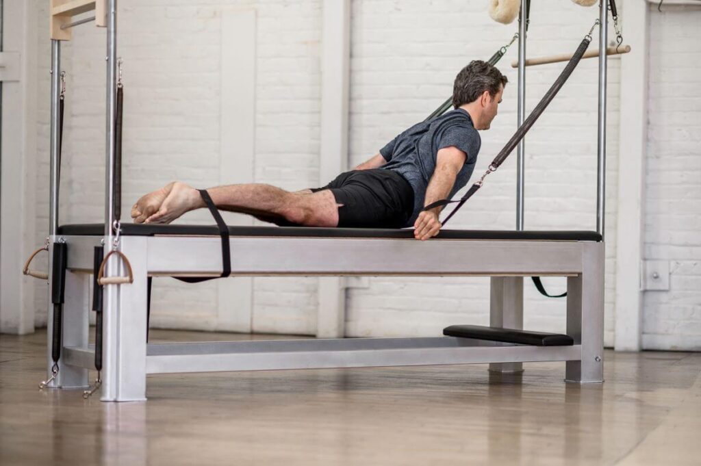 Vīrietis izmanto Contrology Cadillac JPack atsperes Pilates vingrinājumam.