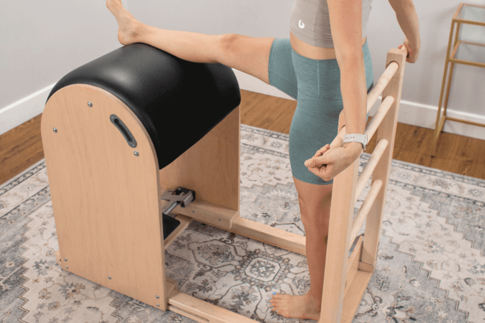 Persona izmanto Balanced Body kāpņu mucu Pilates stiepšanās vingrinājumiem.