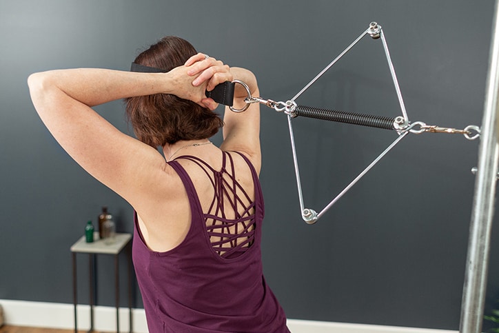 Persona demonstrē Contrology kakla stiepšanas ierīci uz Cadillac trenažiera.