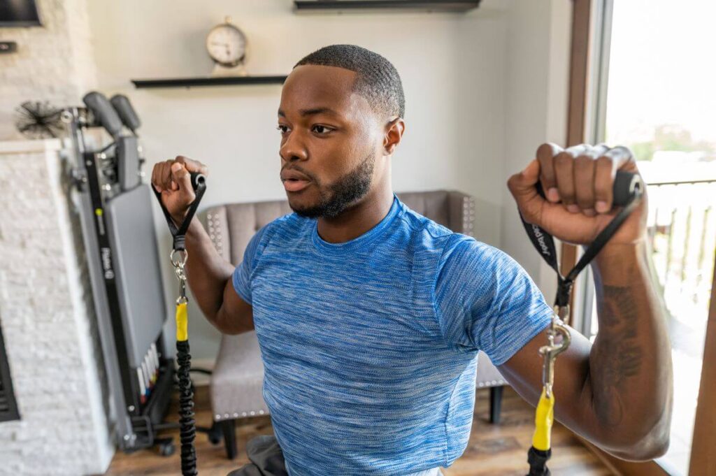 Мужчина занимается с неопреновыми ручками Balanced Body дома.