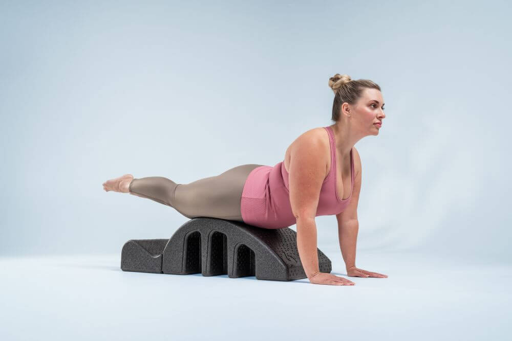 Женщина выполняет упражнение на дуге для пилатеса для укрепления позвоночника.