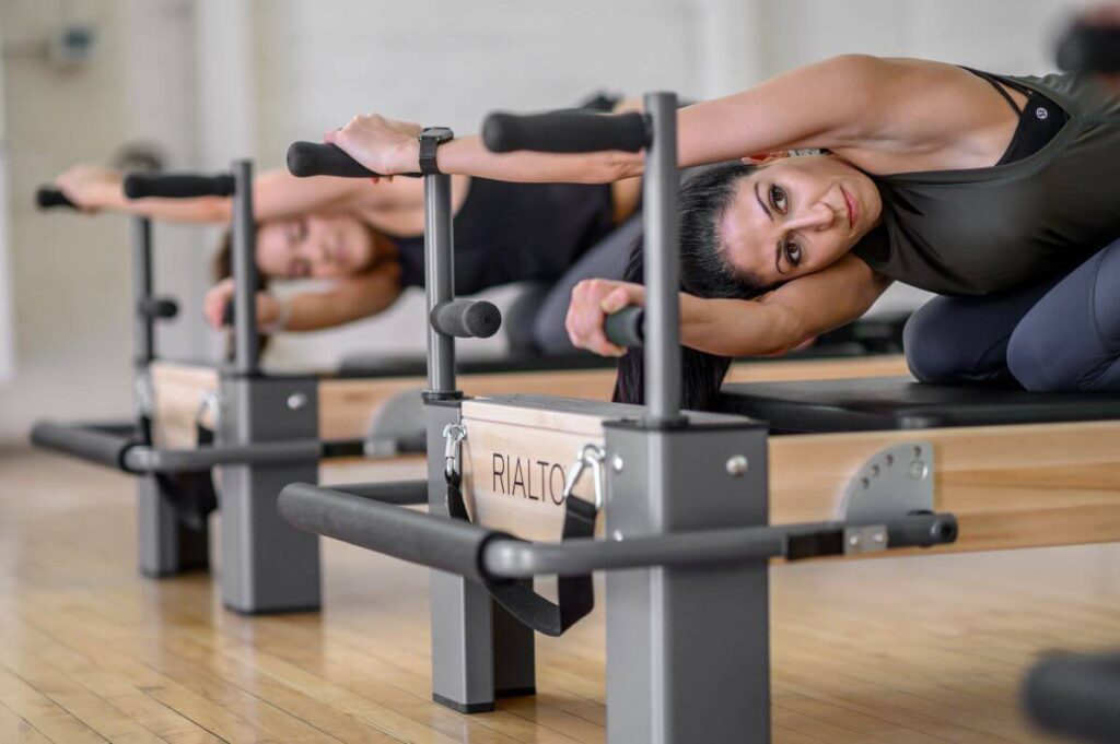 Pilates treniņš, izmantojot Rialto Reformer Plank stieņus roku atbalstam.