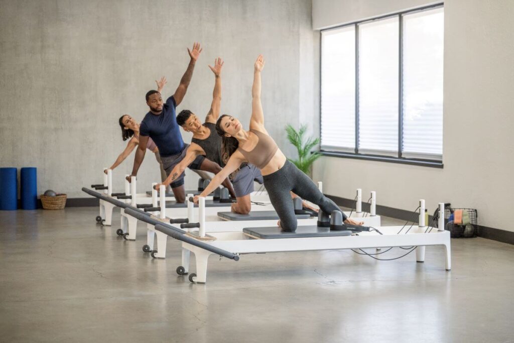 Fitnesa entuziasti izmanto Allegro 2 Reformer Plank stieņus studijā.