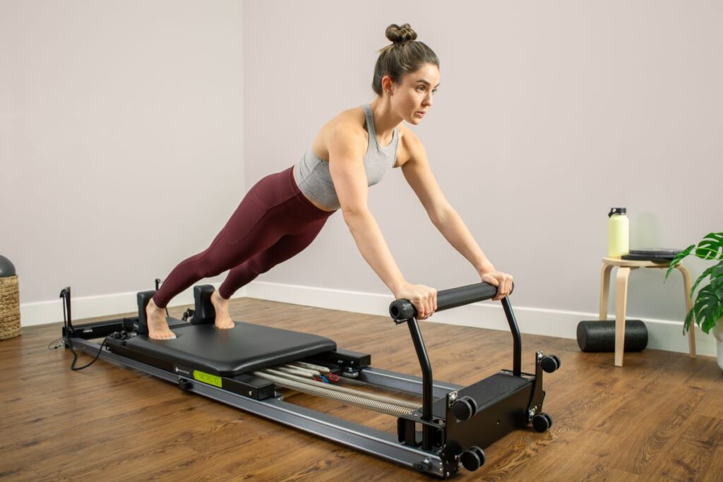 Sieviete vingro uz Pilates Metro IQ Reformer mājas apstākļos