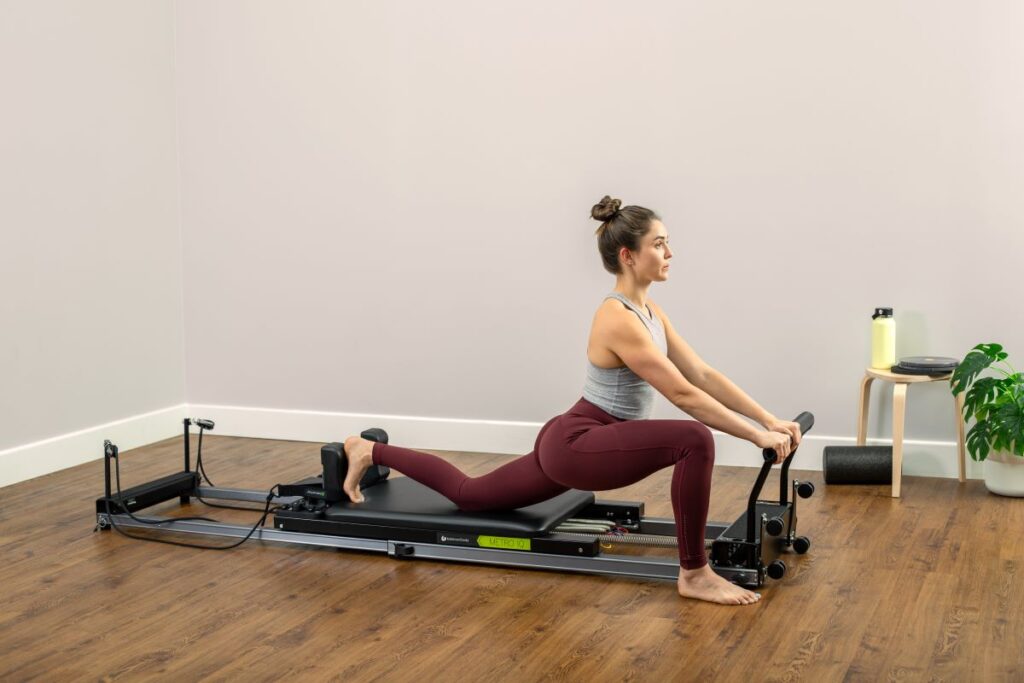 Sieviete vingro uz Metro IQ Reformer mājas apstākļos.