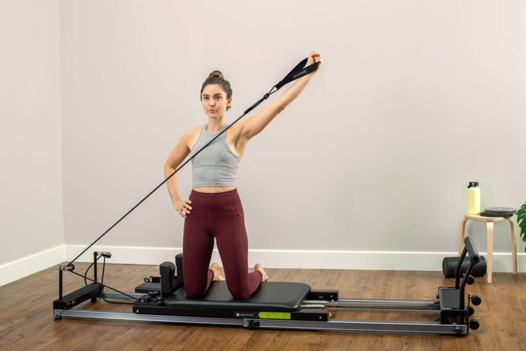 Sieviete izmanto Reformer Signature atsperes Pilates vingrinājumam.