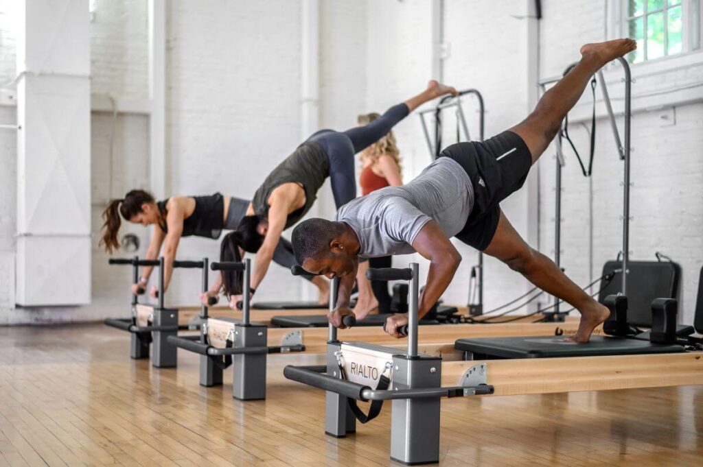 Pilates nodarbība, izmantojot Rialto Reformer dēļu stieņus dēļu vingrinājumiem.