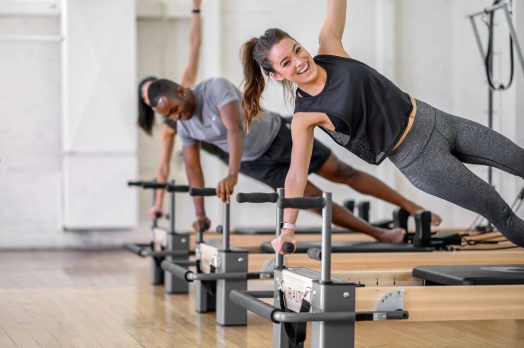 Cilvēki vingro ar Rialto Reformer Plank stieņiem studijā.