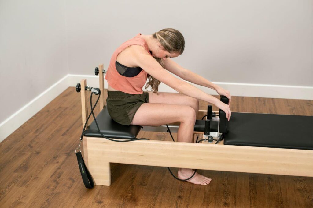 Sieviete izmanto Studio Add-A-Platform uz Balanced Body Reformer trenažiera.