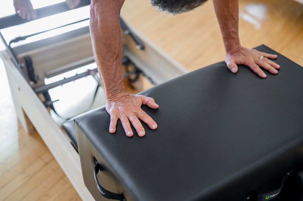 Persona izmanto Ņujorkas sēdēšanas kasti uz Pilates reformera.