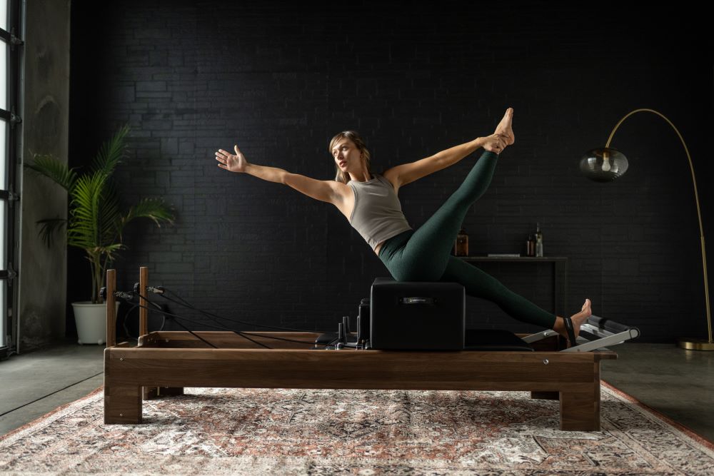 Sieviete vingro uz Reformer trenažiera ar New York Sitting Box studijā.