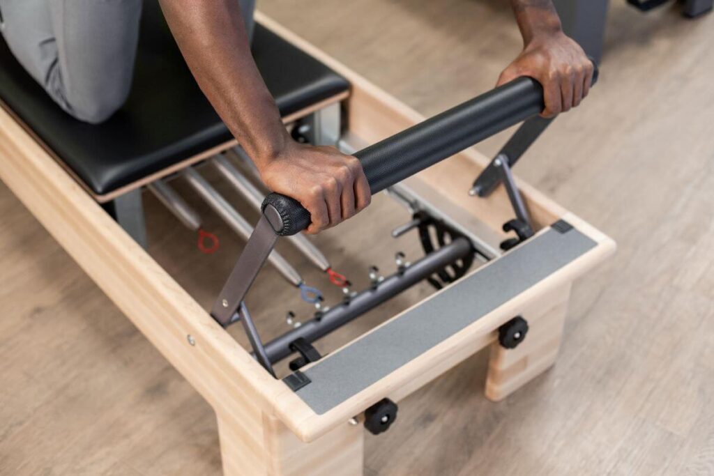 Persona pielāgo Reformer Signature atsperes uz Pilates trenažiera.
