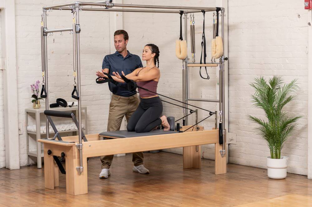 Instruktors palīdz klientam uz Reformer Trapeze Combination trenažiera.