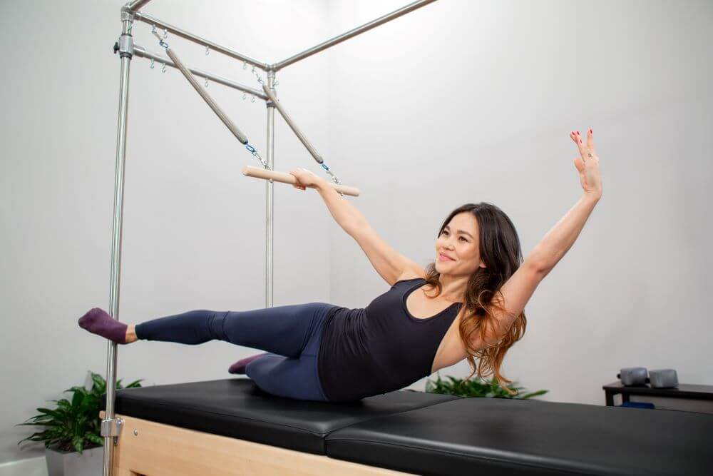 Sieviete vingro uz Reformer Trapeze Combination trenažiera studijā.
