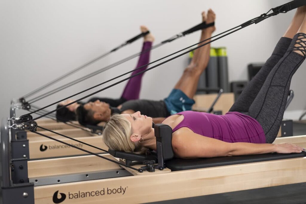 Pilates grupa studijā, izmantojot Rialto Reformer trenažierus.