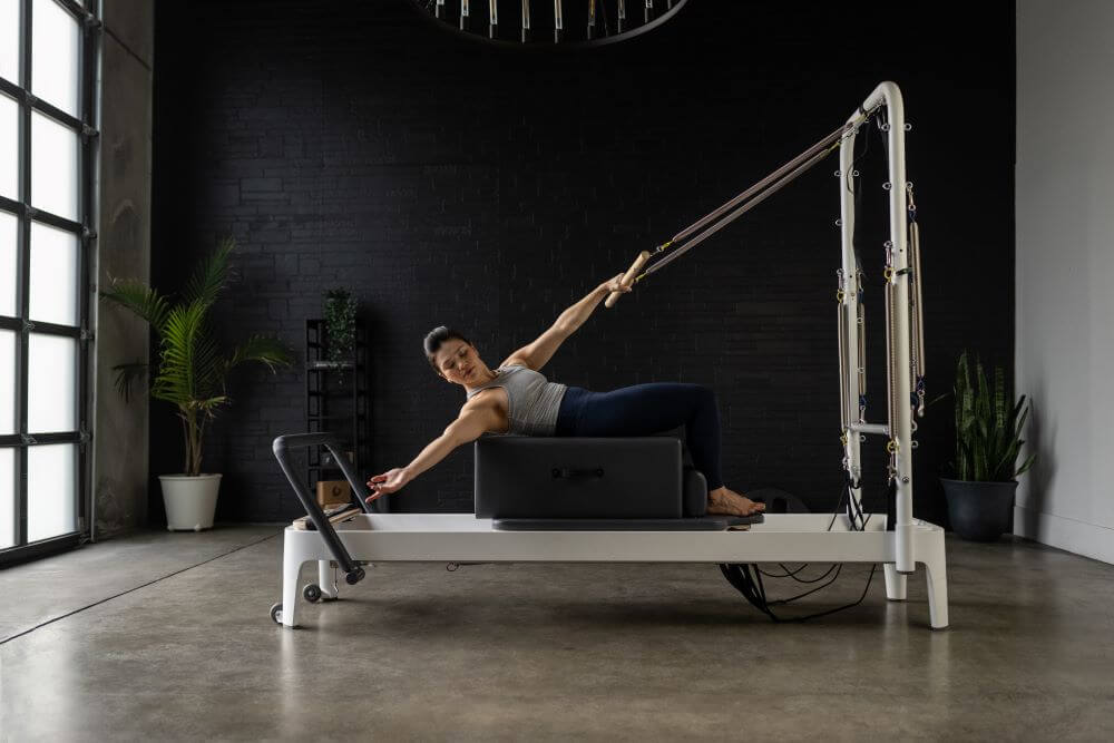 Pilates instruktors izmanto standarta sēdēšanas kasti uz reformera.